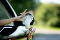 A young woman throws waste from the car - a coffee cup and a bag. Environmental pollution, selective focus, backlight Royalty Free Stock Photo