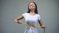 Young woman tightening measuring tape, torturing herself with diet, bulimia