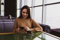 Young woman dials a number on the phone while sitting in a cafe Royalty Free Stock Photo