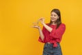 Young woman to red blouse holds grocery cart on her hand. Portrait of girl with shopping cart on the palm of her hand on yellow