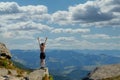 The young Woman at the top of the mountain raised her hands up on blue sky background. The woman climbed to the top and enjoyed Royalty Free Stock Photo