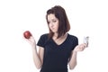 Young woman torn between a chocolate bar and fresh apple