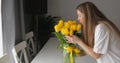 Young woman touch bouquet inhales scent of summer yellow tulip flowers. Glass Royalty Free Stock Photo
