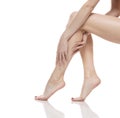 Young woman touching her smooth long legs, and putting on moisturizer after shaving her legs Royalty Free Stock Photo