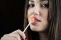 Young woman touching a lollipop on her juicy big lips