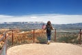 Young woman tourist with american flag admiring of amazing view of Bryce Canyon National Park, Utah, USA