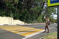 Young woman tourist with backpack crosses the road on pedestrian crossing in the suburbs