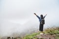 Young woman tourist with backpack relaxing on top of a mountain and enjoying the view of the misty valley Royalty Free Stock Photo