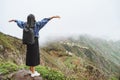 Young woman tourist with backpack relaxing on top of a mountain and enjoying the view of valley Royalty Free Stock Photo
