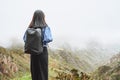 Young woman tourist with backpack relaxing on top of a mountain and enjoying the view of valley Royalty Free Stock Photo