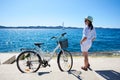 Young woman tourist biker with city bicycle in the town near the sea