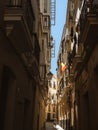 A young woman tourist in a blue dress walking down a narrow old town street in Cadiz under a Spanish flag, Andalusia, Spain Royalty Free Stock Photo