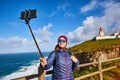 Young woman tourist at Cape Caba da Roca take a selfie shoots with view on beautiful landscape on a mobile phone, winter trip to Royalty Free Stock Photo