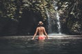 Rear view of Young woman tourist with straw hat in the deep jungle with waterfall. Real adventure concept. Bali island. Royalty Free Stock Photo