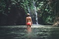 Rear view of Young woman tourist with straw hat in the deep jungle with waterfall. Real adventure concept. Bali island. Royalty Free Stock Photo