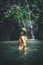 Young woman tourist with straw hat in the deep jungle with waterfall. Real adventure concept. Bali island. Royalty Free Stock Photo