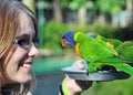 Young woman tourist happy smiling feeding Australian Rainbow Lorikeets birds