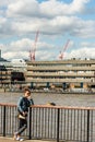 Young Woman Tourist Looking Bored Or Lost Leaning on a Fence Overlooking the River Thames Deep