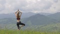 Young woman tourist raising her hands in yoga gestion while hiking in summer mountains.
