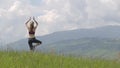 Young woman tourist raising her hands in yoga gestion while hiking in summer mountains.