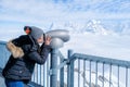 Young Woman Tourist at the Schilthorn using coin operated binocular to enjoy the magnificent panoramic view of the Swiss Skyline