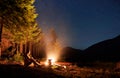 Female traveler sitting near campfire under night starry sky. Royalty Free Stock Photo