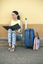 Young woman tourist sitting with luggage and a travel brochure i