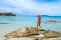 Young woman tourist standing on a rock and looking at crystal clear turquoise sea water at Punta Molentis beach, Sardinia island, Royalty Free Stock Photo