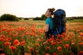 Young woman tourist stands on field of red poppies. Royalty Free Stock Photo