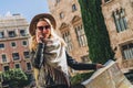 Young woman tourist stands on street of ancient European city and holds map. In background is beautiful building. Royalty Free Stock Photo