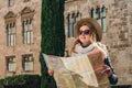 Young woman tourist stands on street of ancient European city and holds map. In background is beautiful building. Royalty Free Stock Photo