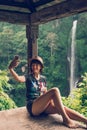 Young woman tourist taking selfie photo of the Sekumpul waterfall, magic island of Bali, Indonesia. Royalty Free Stock Photo