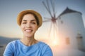 Young woman tourist is taking a selfie picture in front of a windmill and sunset in oia, santorini Royalty Free Stock Photo