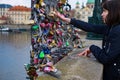 Young woman tourist touches the statue of St. John Nepomuk on Charles bridge on which there are many locks that hang for good luck