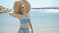 Young woman tourist wearing bikini and summer hat smiling at beach Royalty Free Stock Photo