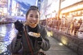 Young woman tourists enjoy eating street food in walking at street shopping center Dotonbori in Osaka, Japan