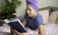 a young woman with a towel on her head is lying in bed and reading a book. The concept of rest, education and time for Royalty Free Stock Photo
