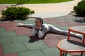 Young woman in a tracksuit lies on the playground in a transverse twine. Front view. Sports, stretching