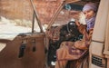 Young woman in traditional Bedouin coat - bisht - and headscarf, sitting in old 4wd vehicle, looking from opened door - blurred