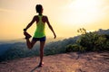 Woman trail runner warming up on mountain top rock