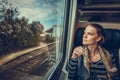 The young woman is on the train and watches through the window o