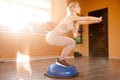 Young woman trainer making squats on bosu balance ball sunlight Royalty Free Stock Photo