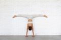 Young woman trainer practicing yoga doing Adho Mukha Vrikshasana exercise with Samakonasana, handstand with transverse splits Royalty Free Stock Photo