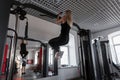 Young woman trainer in sportswear with a slim body doing exercises for hands indoors. Girl performs physical exertion in training