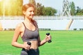 Young woman is training with dumbbells at the stadium. Strong muscles and active sport concept Royalty Free Stock Photo