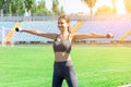 Young woman is training with dumbbells at the stadium. Strong muscles and active sport concept Royalty Free Stock Photo