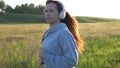Young woman is training in summer in the park at dawn in headphones with music. Free beautiful girl is engaged in