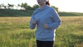 Young woman is training in summer in the park at dawn in headphones with music. Free beautiful girl is engaged in