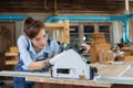 Young woman is training to be a carpenter in workshop. Carpenter working with equipment on wooden table. woman works in a