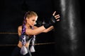 Young woman trains in boxing ring with heavy punching bag. Royalty Free Stock Photo